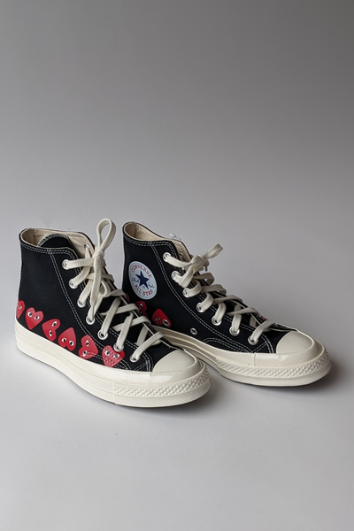 Front, side view of Comme des Garçons PLAY Multi Heart Converse Chuck Taylor High Top shoes.