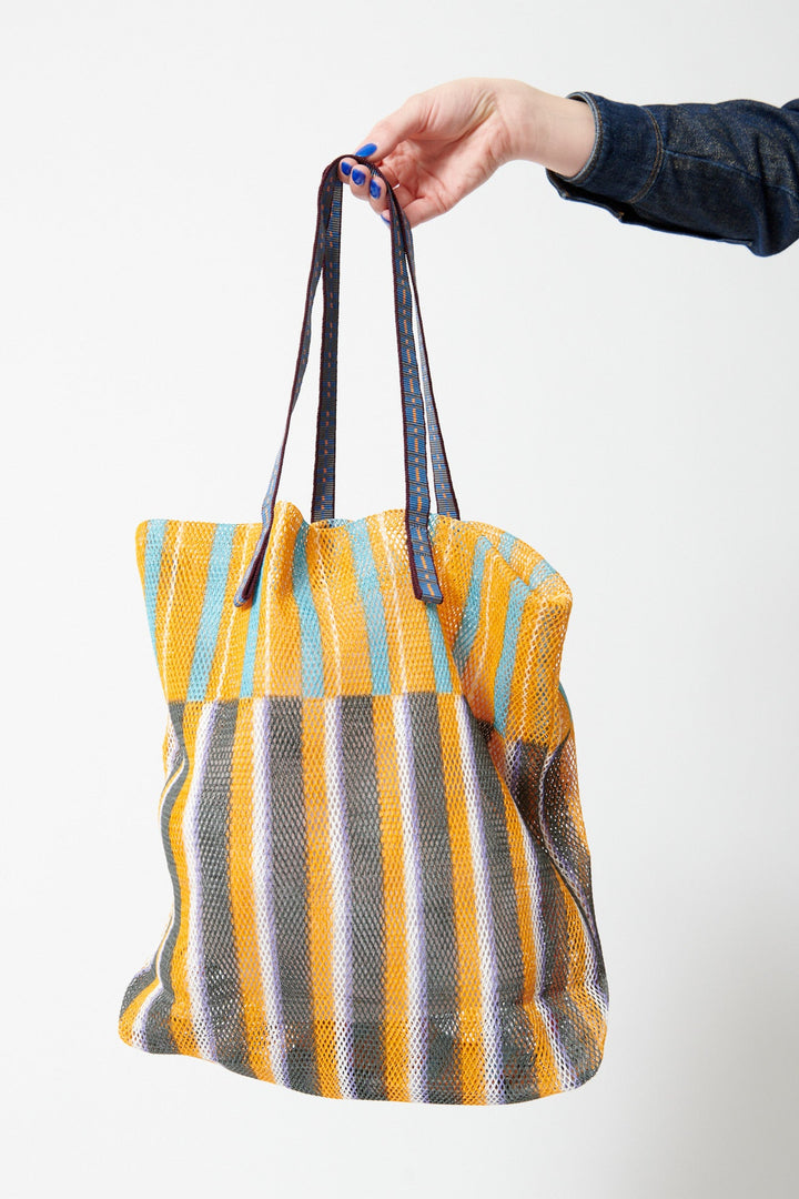 Model holding Épice Extra Large Stripe Mesh Tote front view