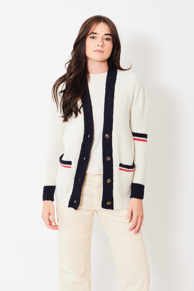 Front view of model wearing ivory cardigan with buttons and navy and red details