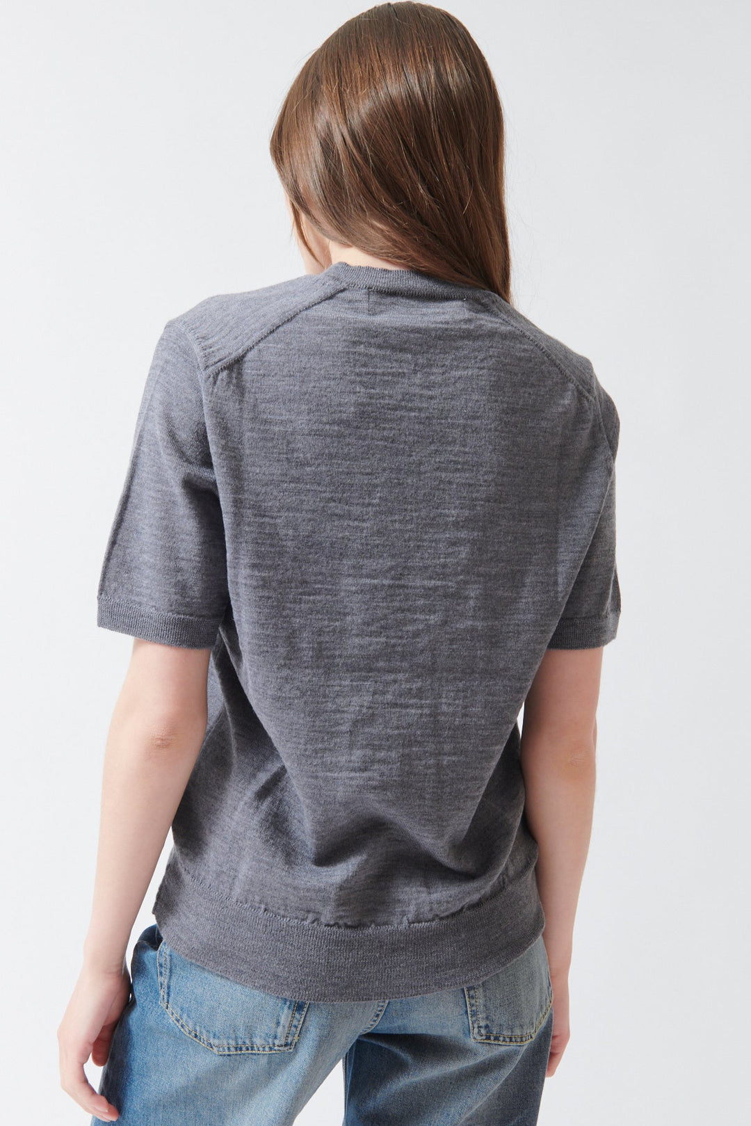 Angela wearing Comme des Garçons PLAY Red Heart Emblem Short Sleeve V Sweater Grey rear view