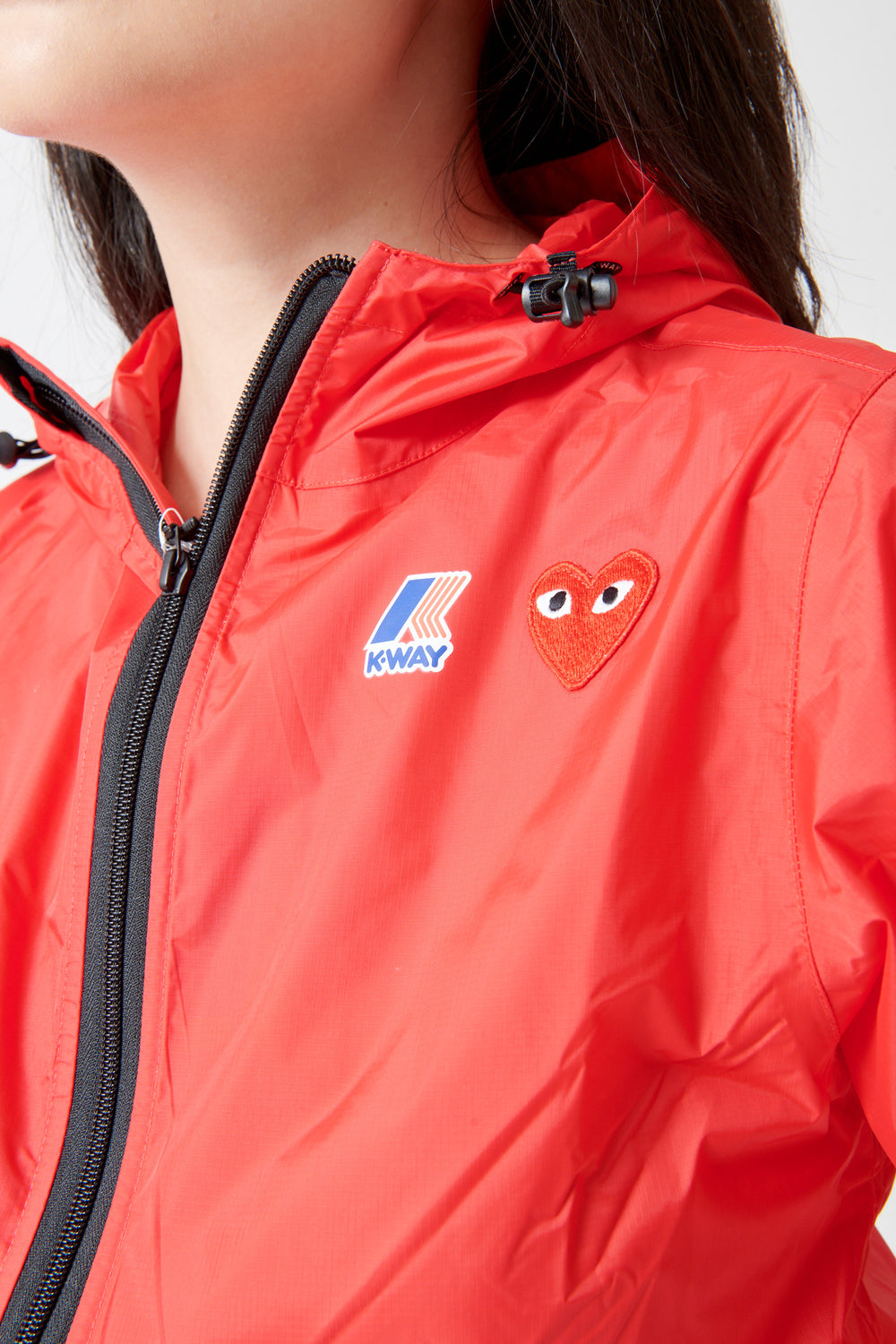 Lilly wearing Comme des Garçons PLAY K-Way Full Zip Red Emblem Unisex Jacket Red front/detail view