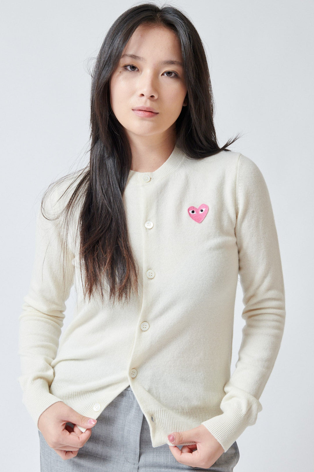 Lilly wearing Comme des Garçons PLAY Pink Emblem Round Neck Cardigan Natural front view
