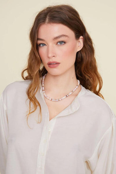 Close-up view of model wearing pearl white long-sleeved blouse
