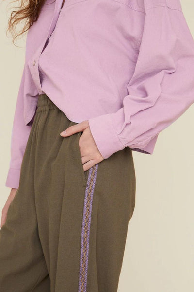 Up-close side view of army green pants with elastic waist and multicolored side stripe