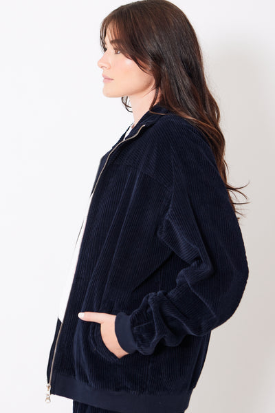 Close side view of model wearing navy blue corduroy zip up jacket