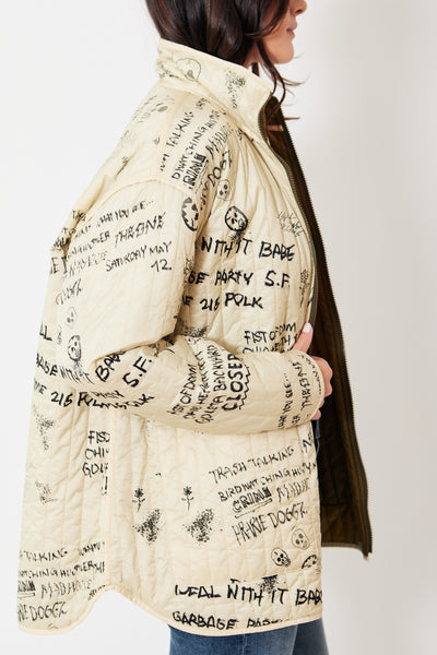 Close-up side view of reversible jacket, cream side with black doodles and words scrawled across it