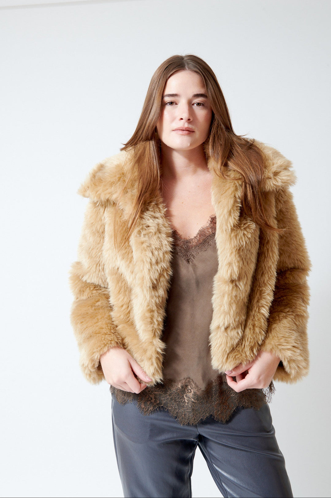 A woman modeling Meimeij a light brown shaggy faux fur jacket over a brown lace-trim camisole and dark gray pants, set against a plain white studio background.